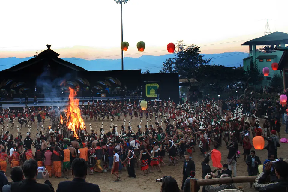 A crowd gathered around a bonfire at a festival ground