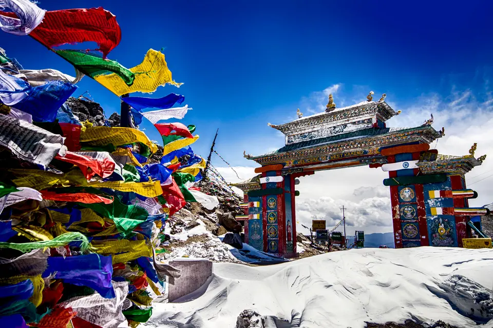 Prayer flags beside a painted monastery gate in the snow
